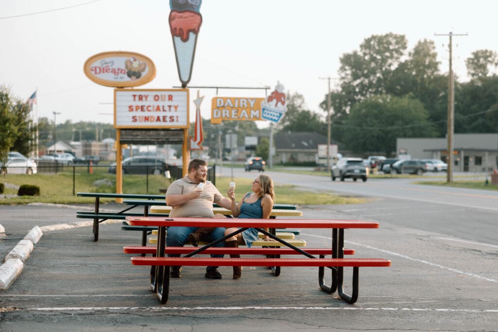 couple sitting at a picnic table with ice cream in hand
